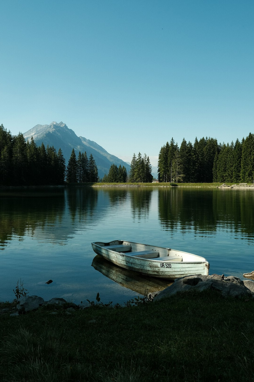 Mountain lake with a small boat and forest